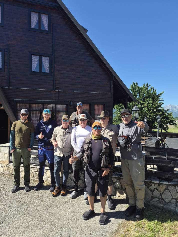 A group of anglers in front of a mountain lodge