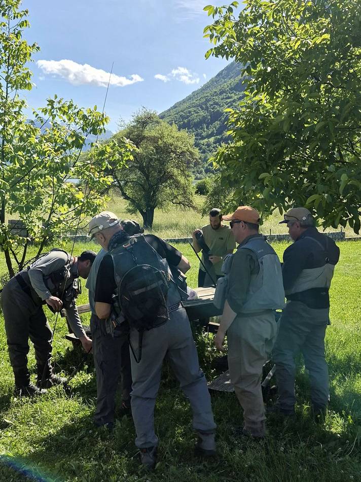 Anglers preparing their gear at a picnic table under the trees