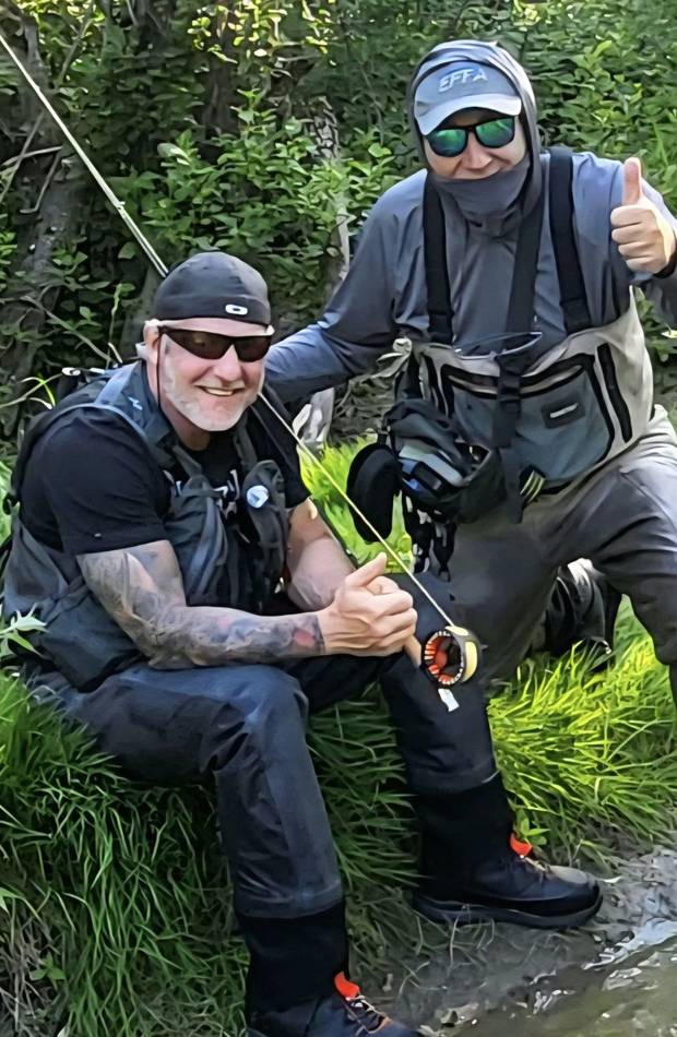 Two anglers on the riverbank giving a thumbs up