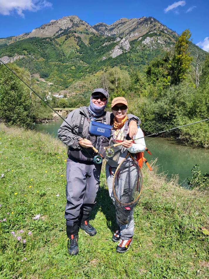 Two anglers with a landing net in front of the mountains