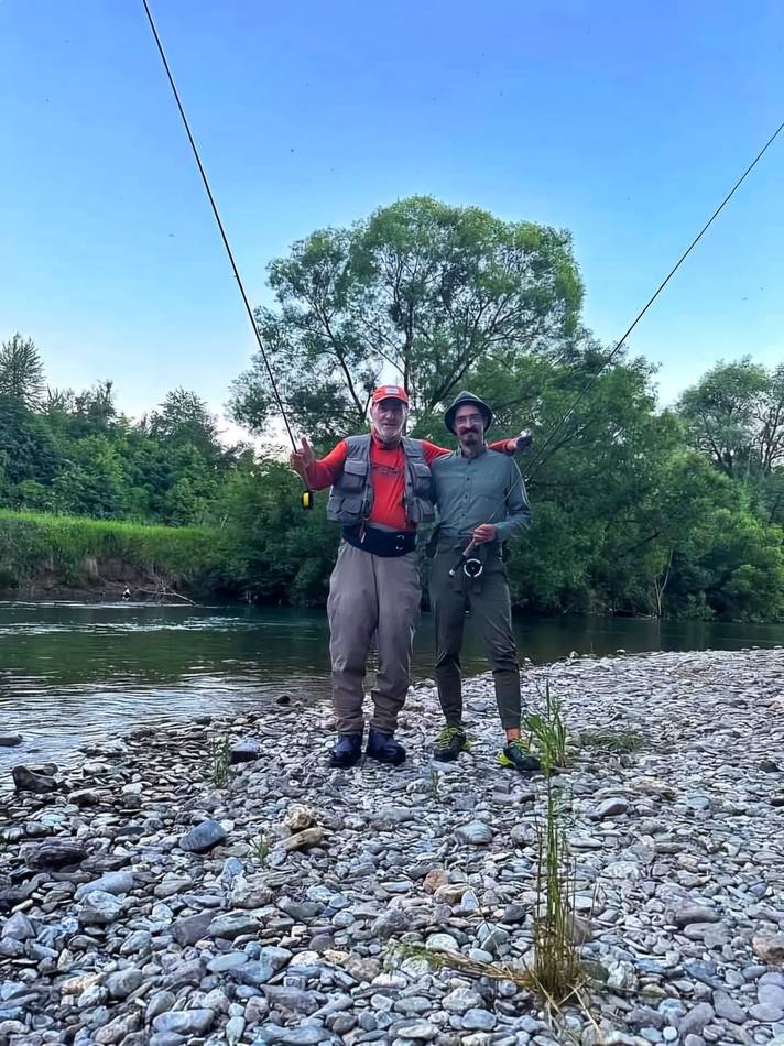 Two anglers on the gravel bank with rods raised