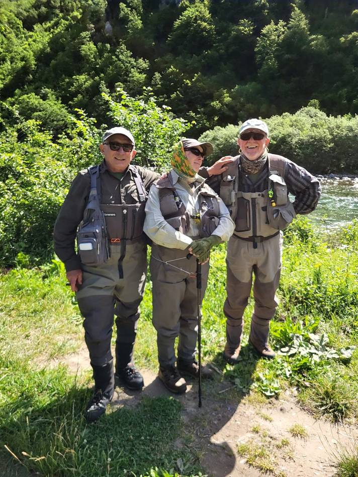 Three anglers laughing together by the river