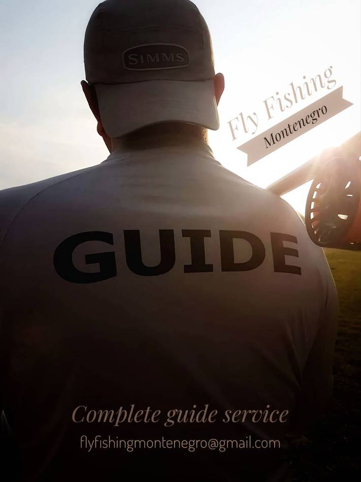 A guide seen from behind at sunrise, rod on his shoulder