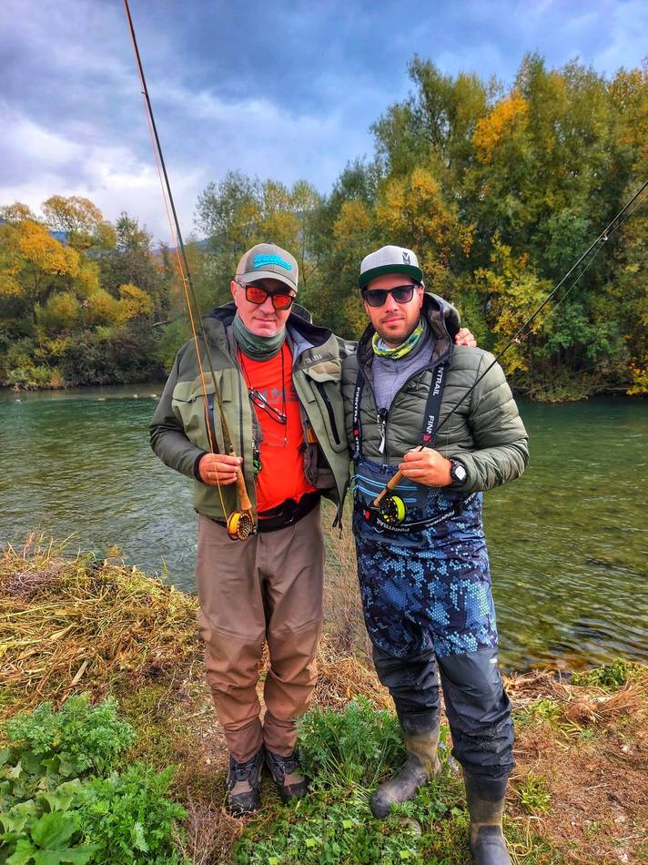 Two anglers on the riverbank in autumn colours