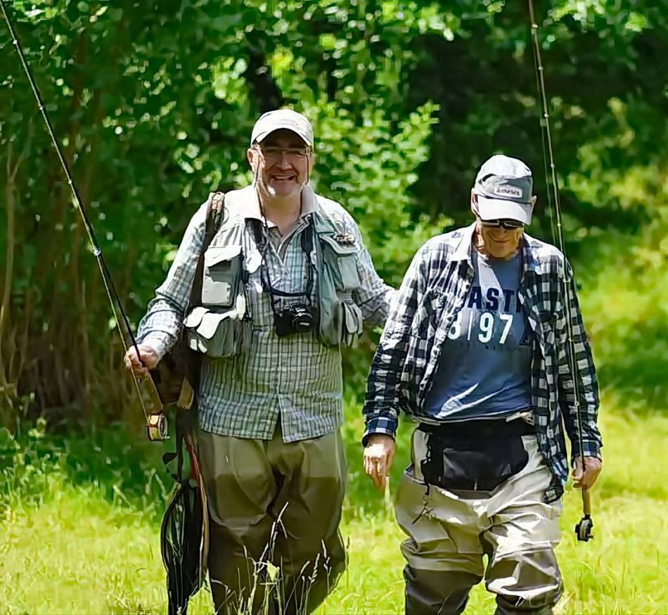 Two anglers walking through the meadow to the river