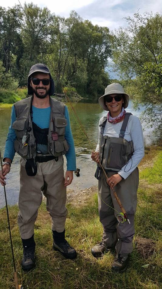 A couple with their fly rods on the riverbank