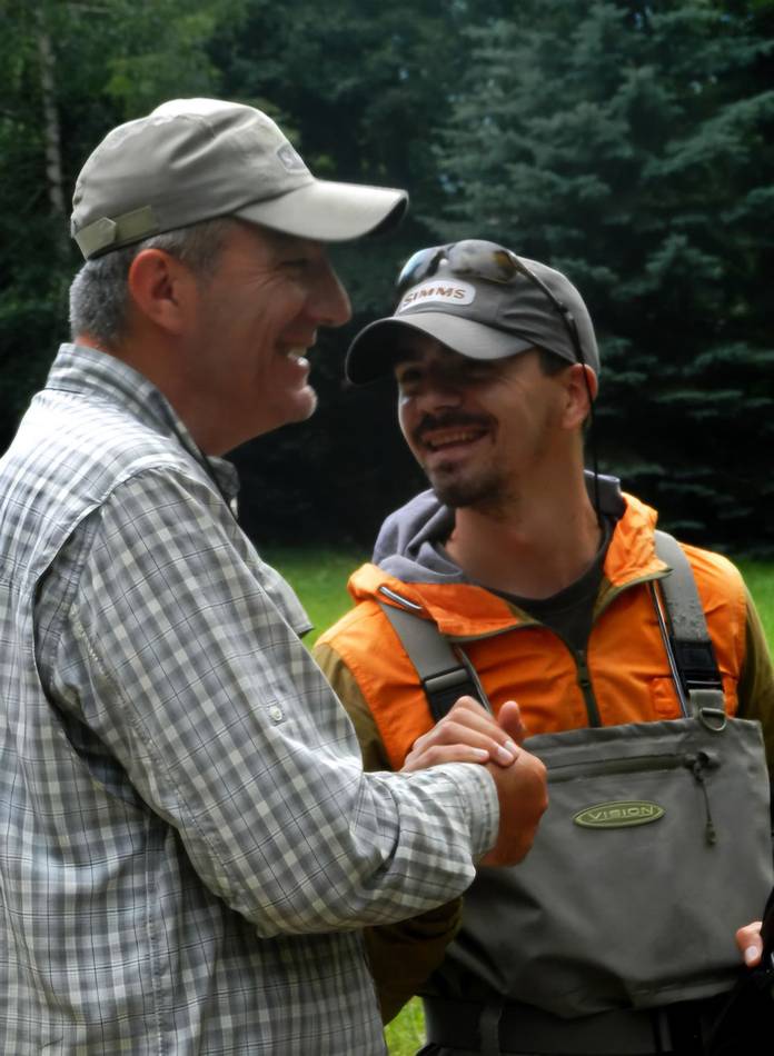 Two anglers shaking hands and laughing