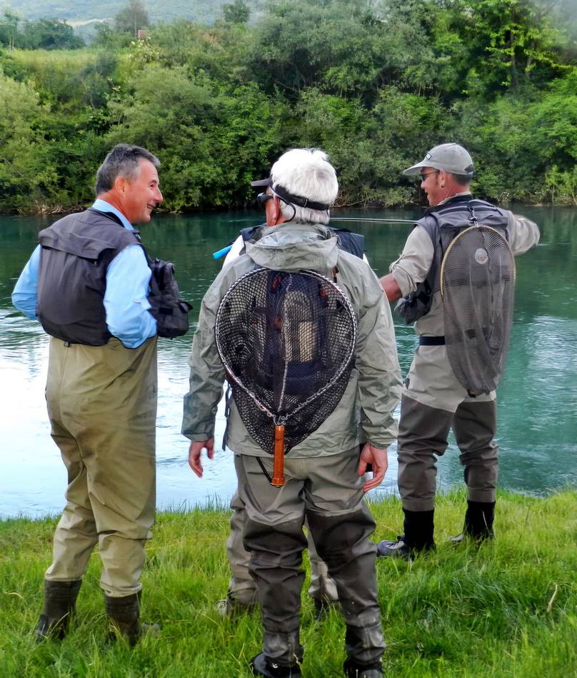 Anglers talking on the riverbank with their landing nets