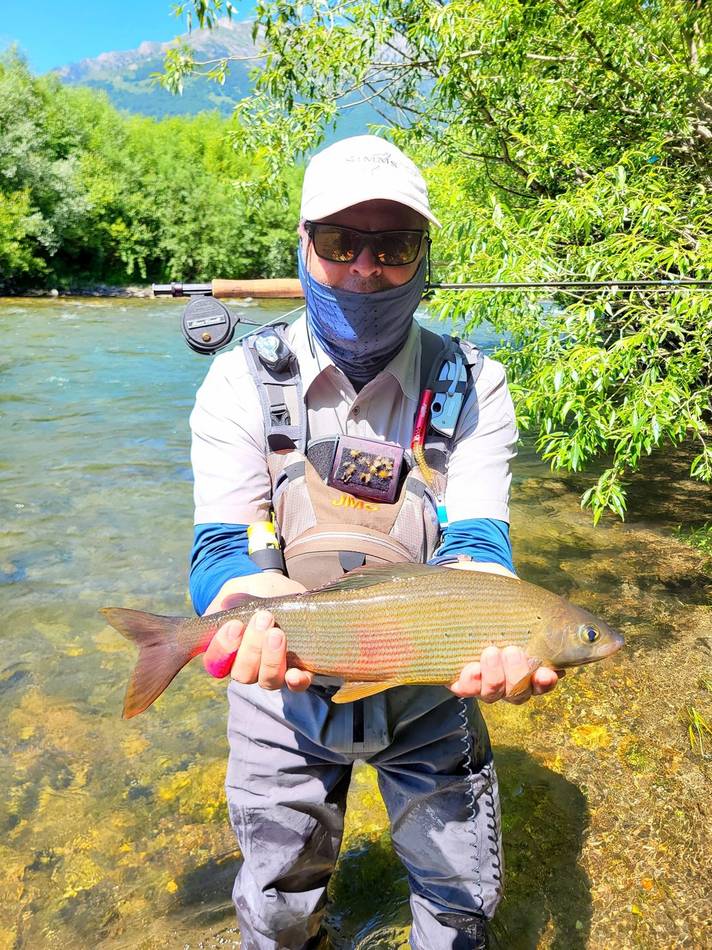 A guest holding his grayling, fly box on his vest