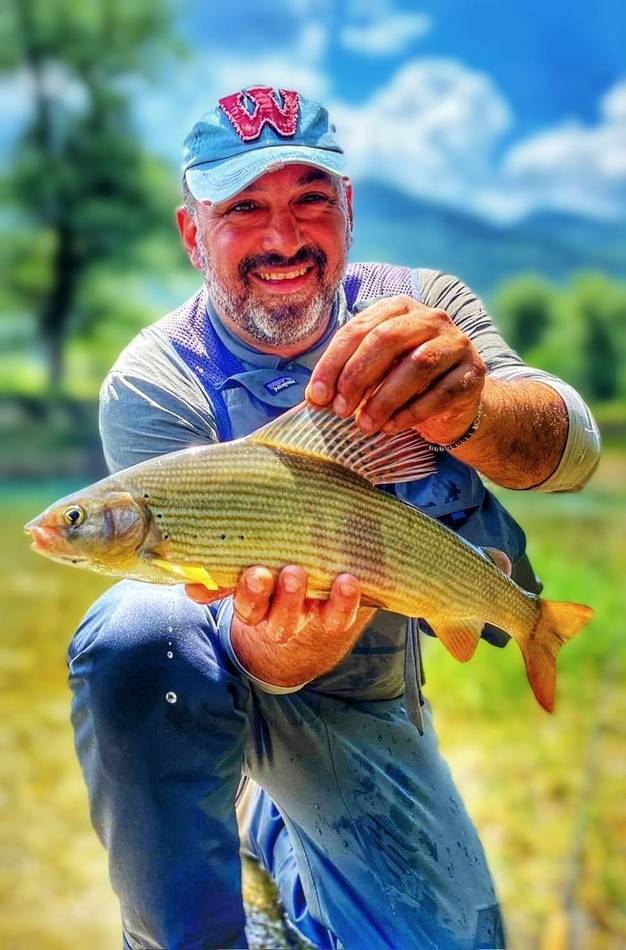 A guest holding his grayling in the evening light