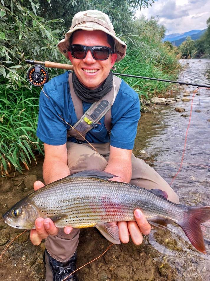 A guest holding his grayling's bright orange-spotted fin