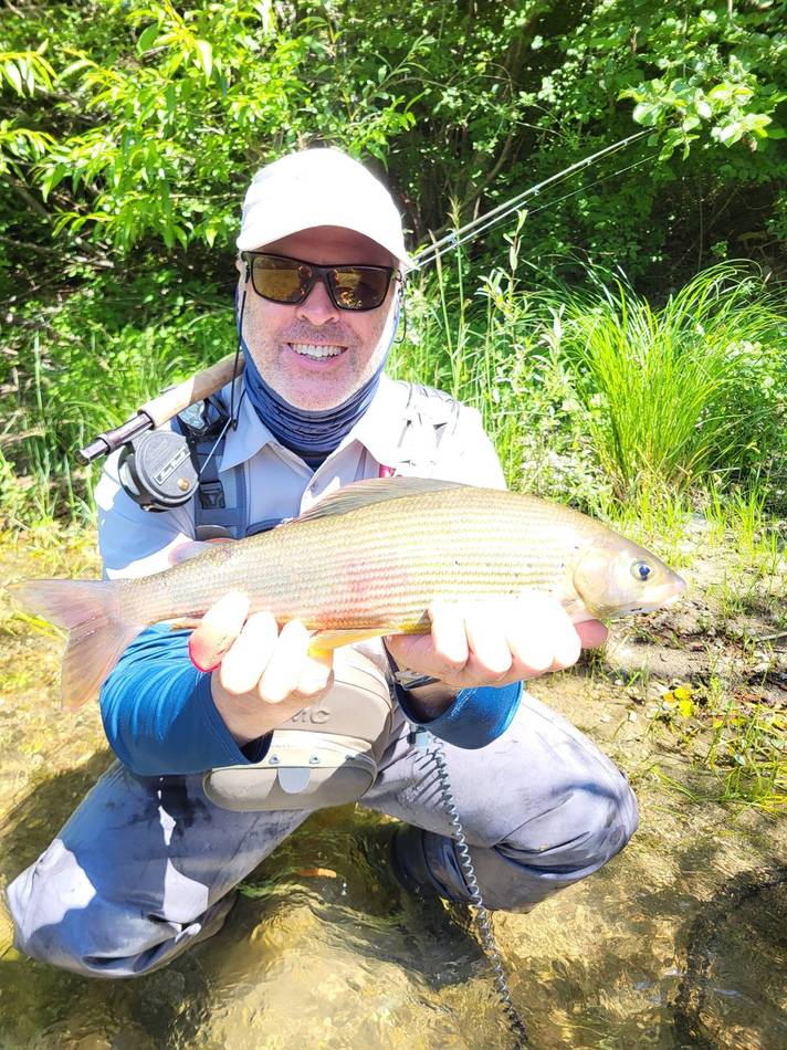 A guest holding his grayling with the rod over his shoulder